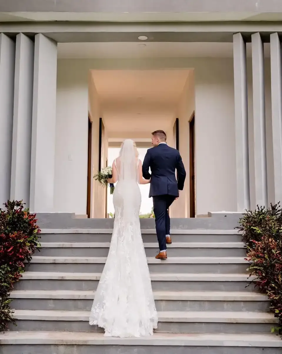 A bride and groom are walking down the stairs of a building.