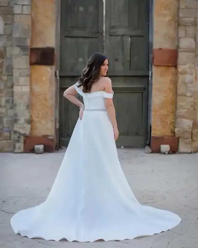 A woman in a white wedding dress is standing in front of a building.
