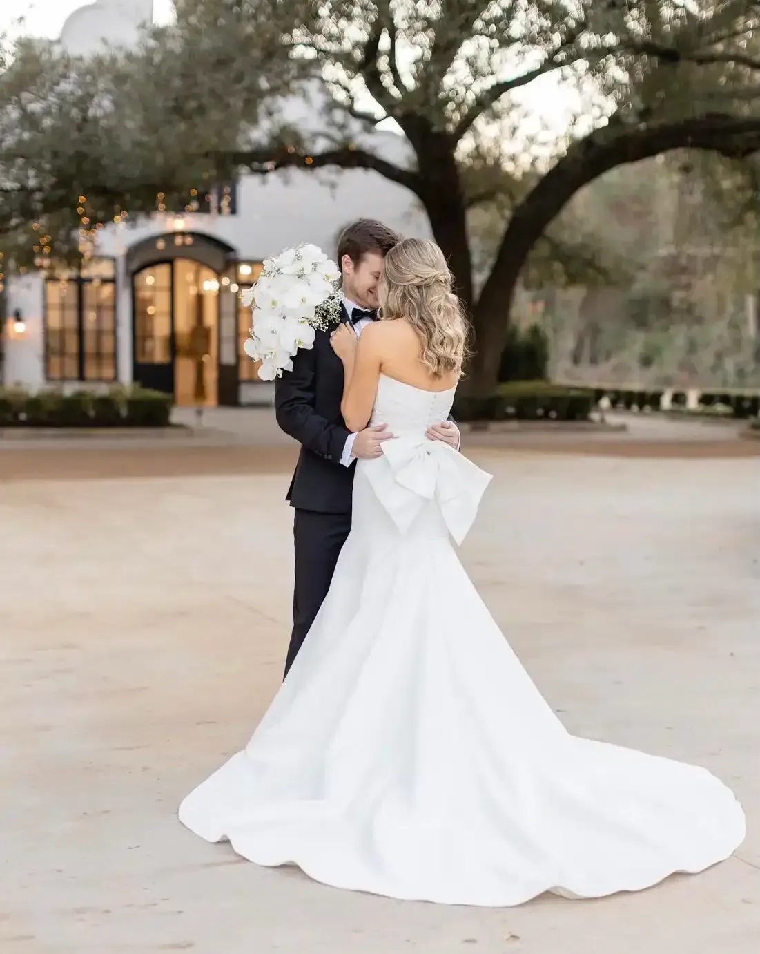 A bride and groom are posing for a picture in front of a building.