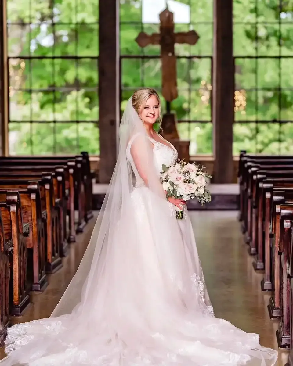 A bride in a wedding dress is standing in a church holding a bouquet of flowers.