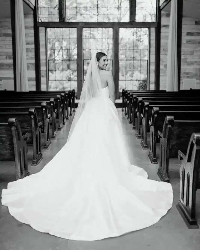 A bride in a wedding dress and veil is standing in a church.