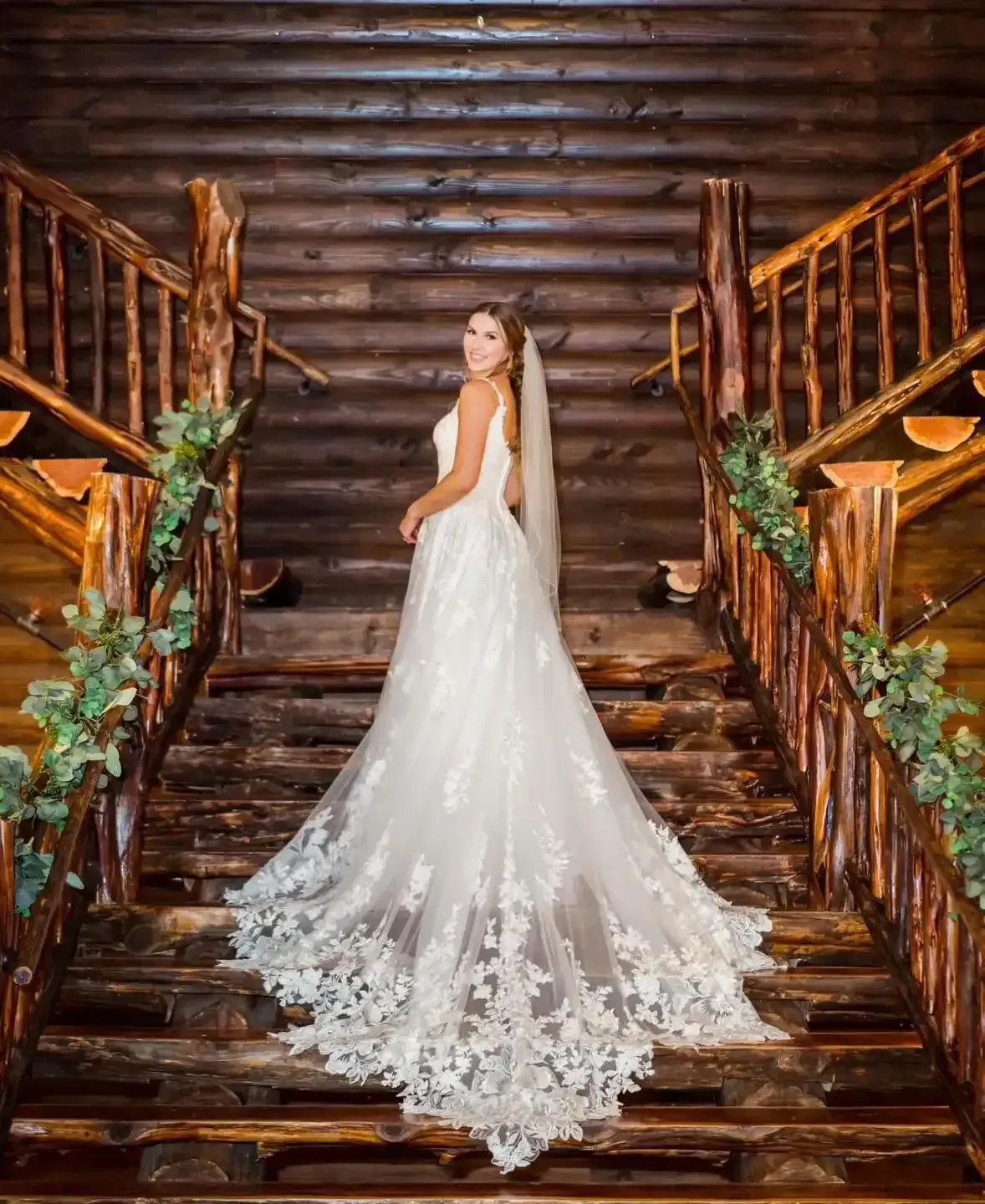 A bride in a wedding dress is standing on a set of wooden stairs.