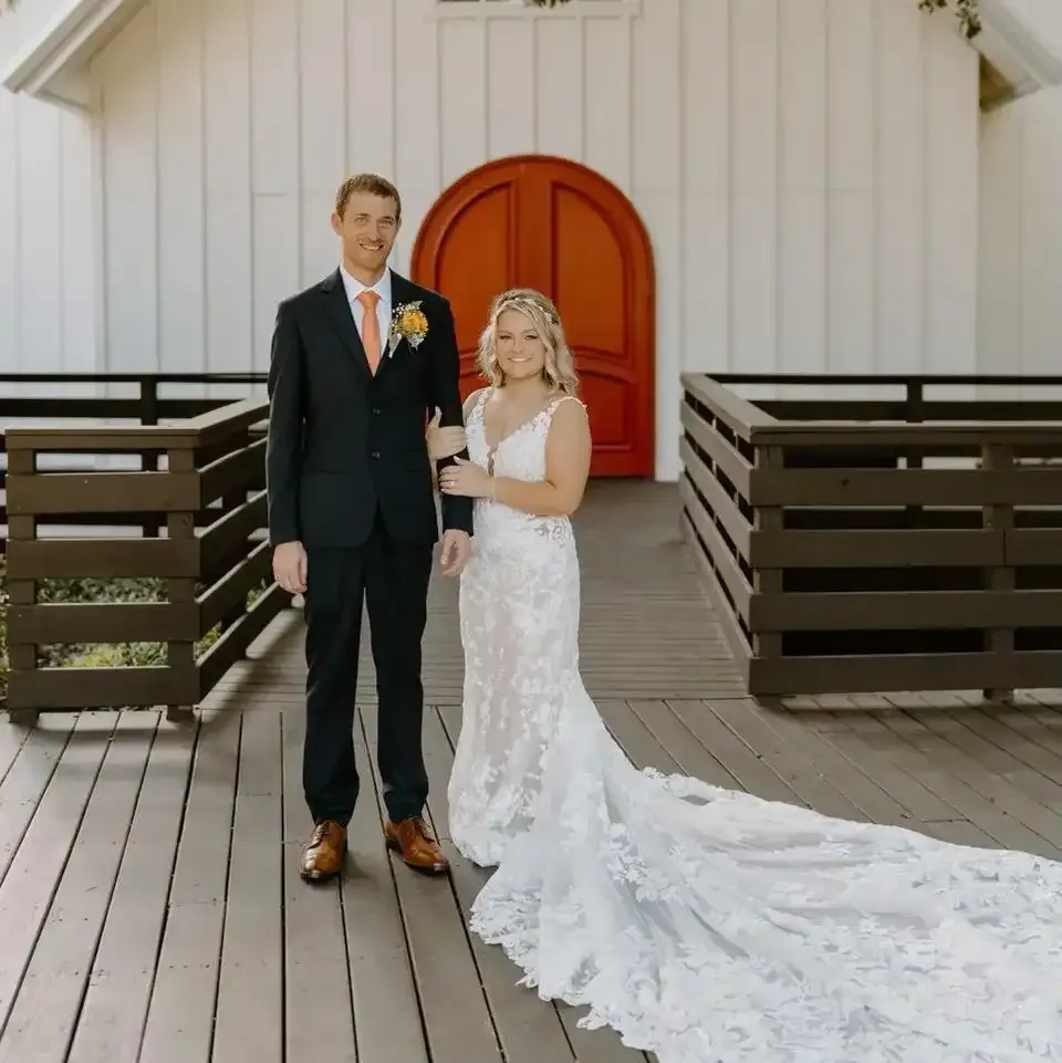 A bride and groom are posing for a picture in front of a church
