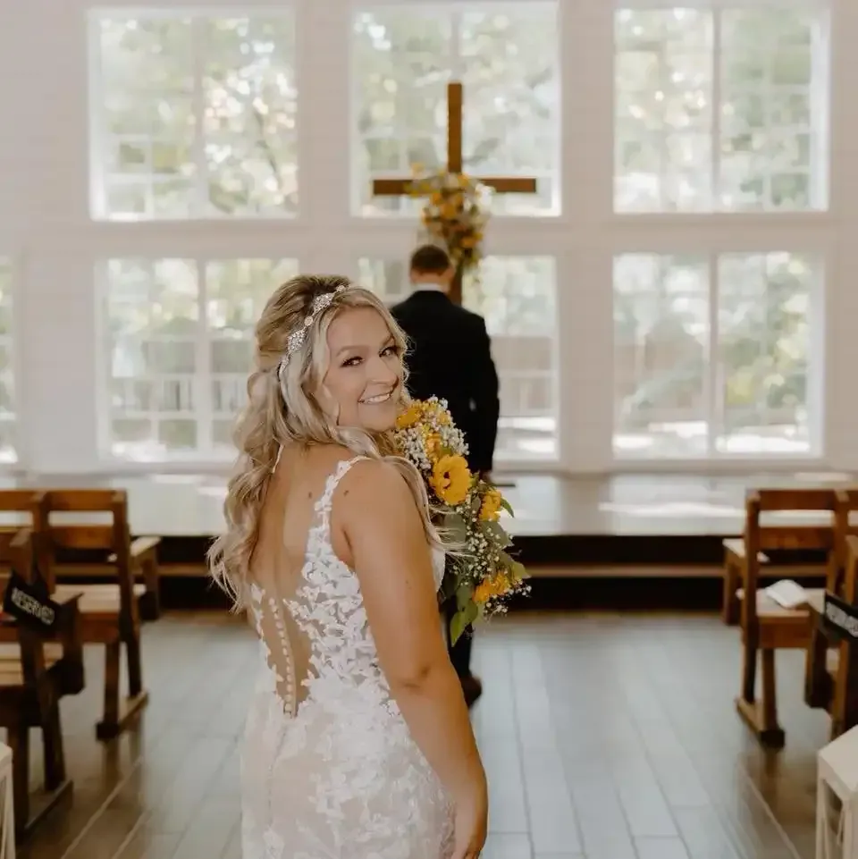 A bride in a wedding dress is holding a bouquet of flowers in a church.