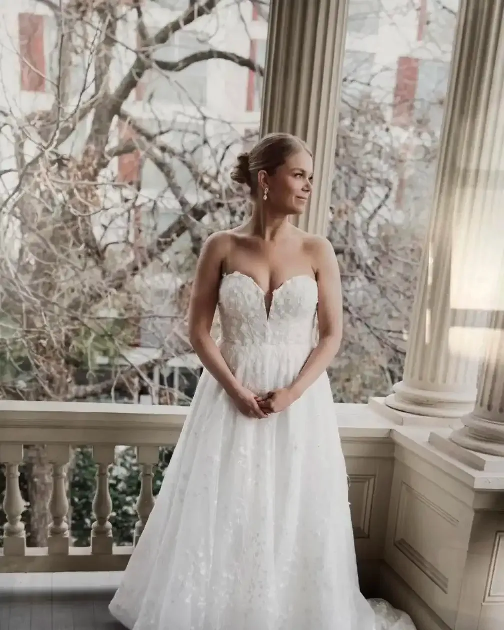 A woman in a wedding dress is standing on a balcony