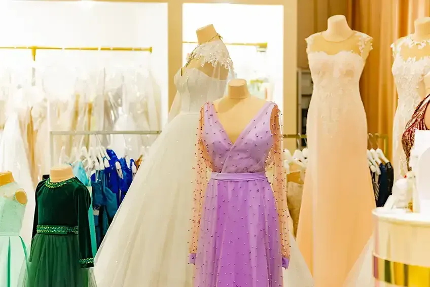 A row of mannequins wearing different dresses in a store.
