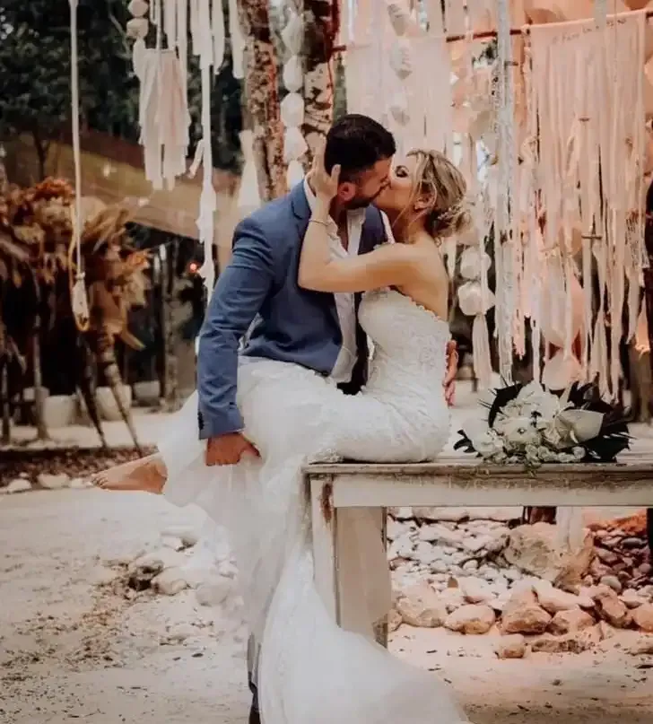 A bride and groom kissing while sitting on a table