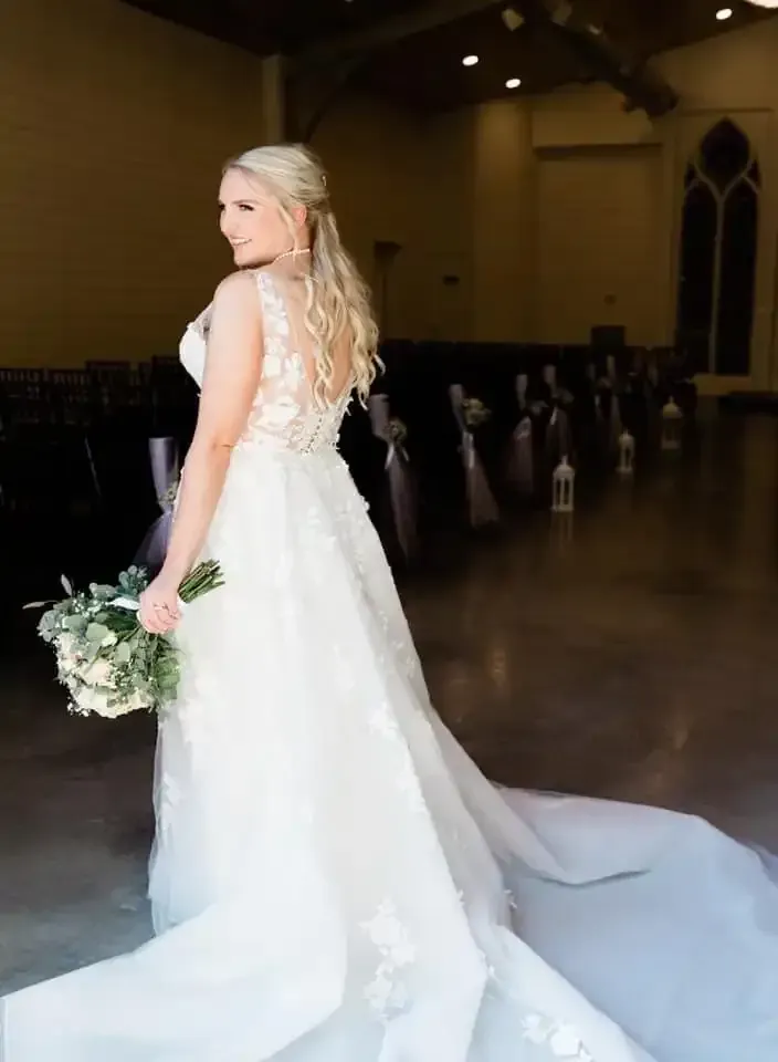 A bride in a wedding dress is standing in a church holding a bouquet of flowers.