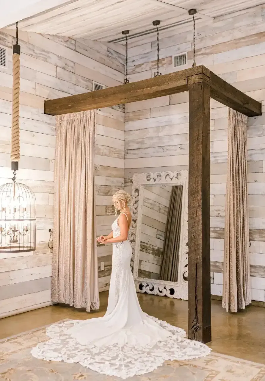 A bride in a wedding dress is standing in a dressing room.