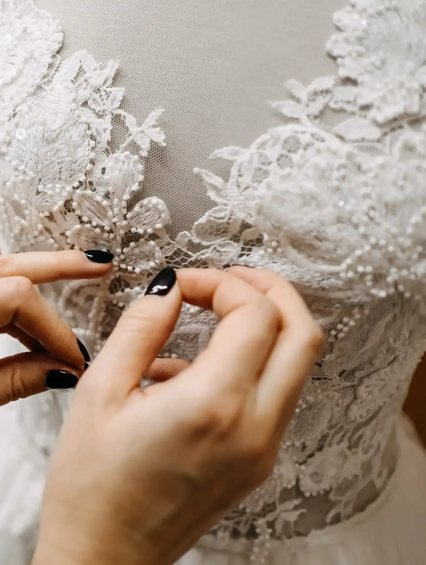 A woman is fixing the lace on a wedding dress.