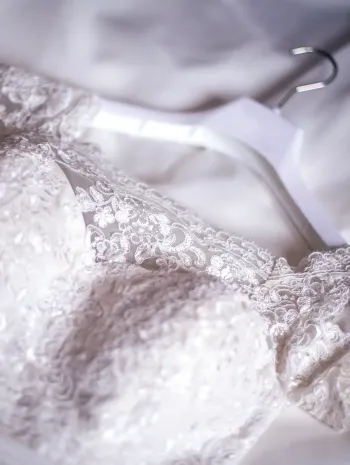 A close up of a white lace bra on a white cloth.