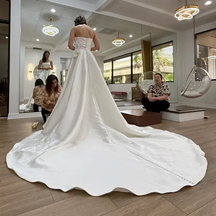 Woman in a white wedding dress with a long train, at Luxury Tailors Atelier by Monica