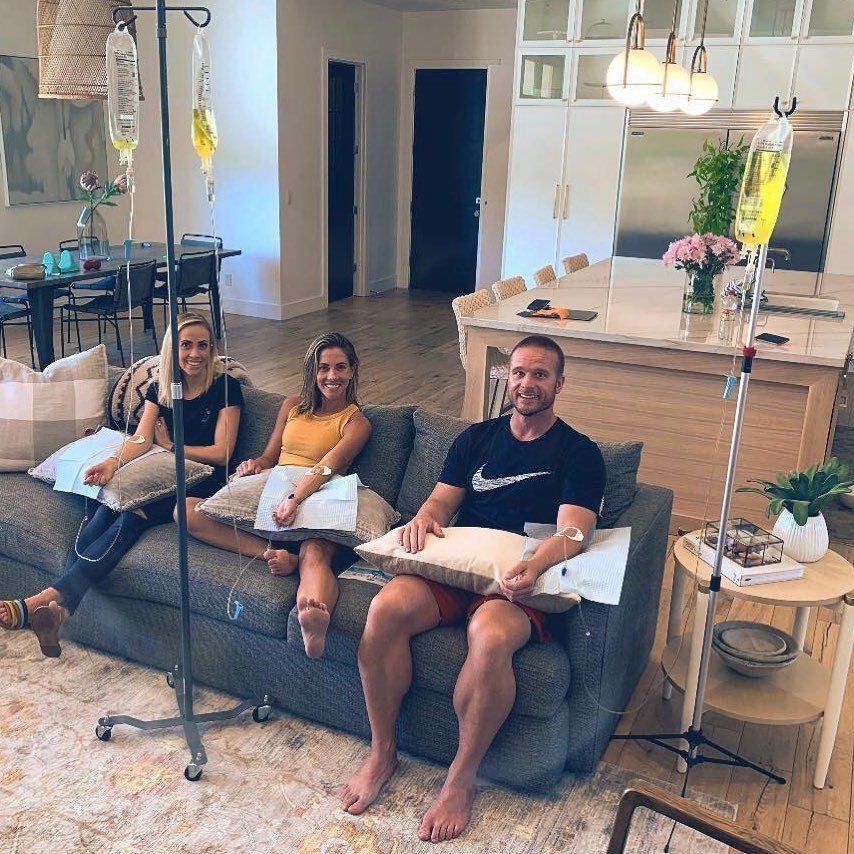 A man and two women are sitting on a couch in a living room.