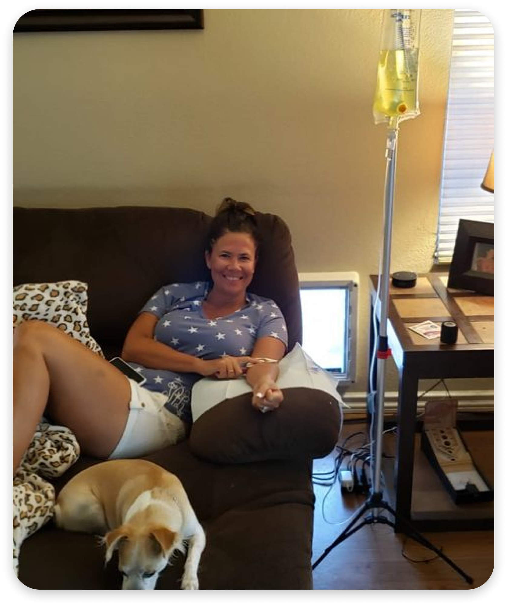 A woman sits on a couch next to a dog