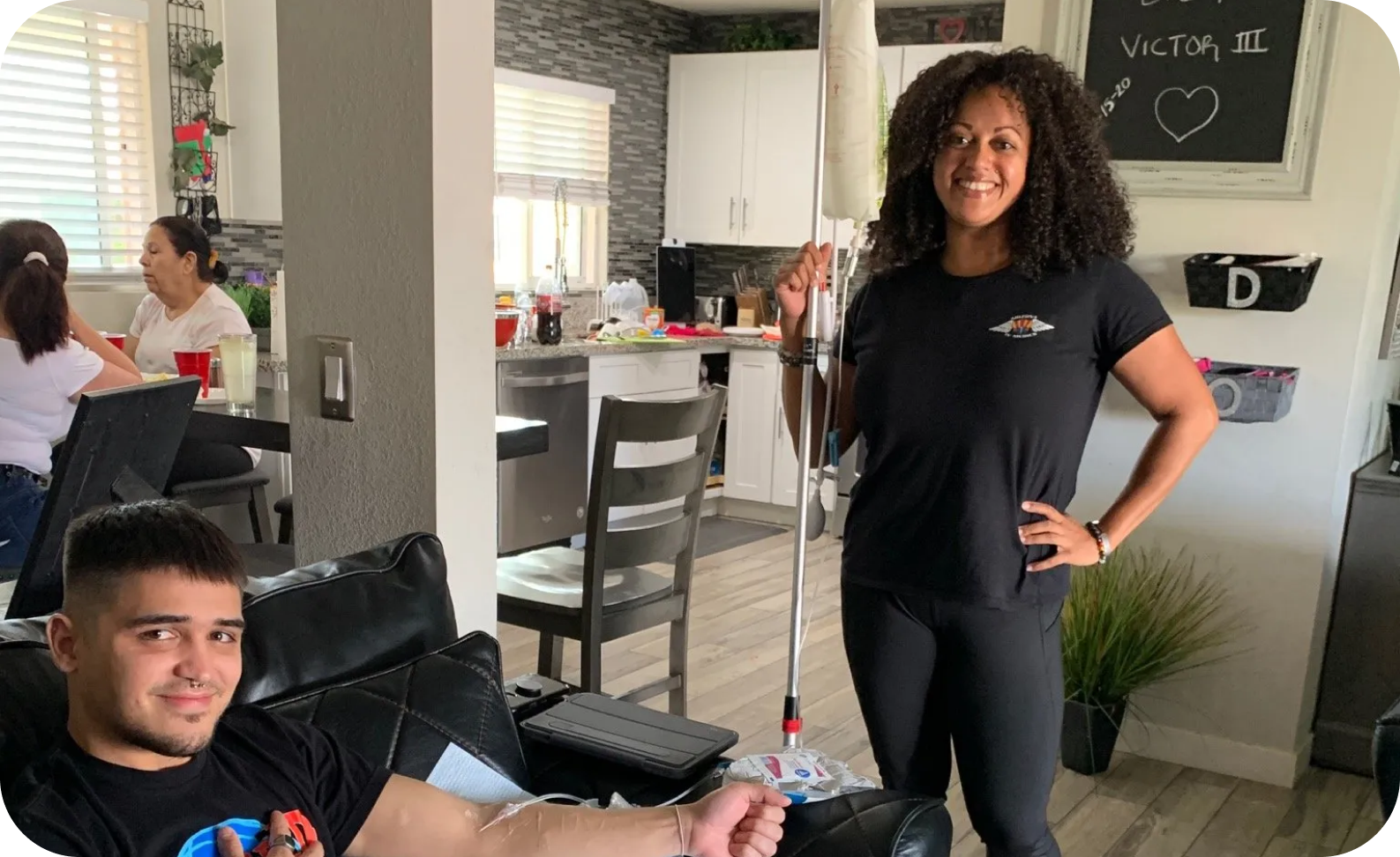 A woman is standing next to a man sitting on a couch in a living room.