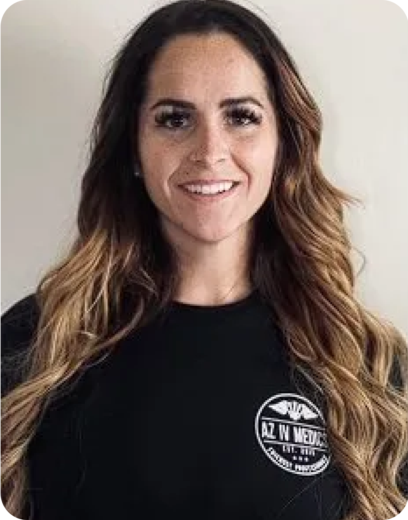 A woman with long hair is wearing a black shirt and smiling.