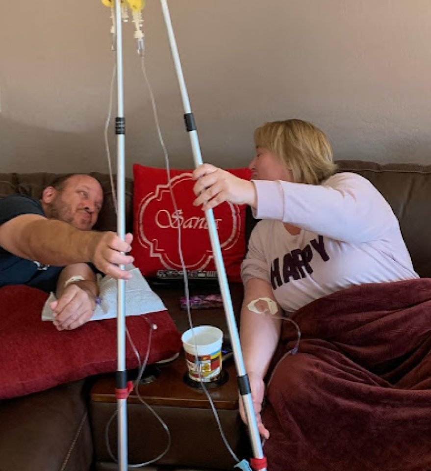 A man and a woman are sitting on a couch with iv drips in their arms