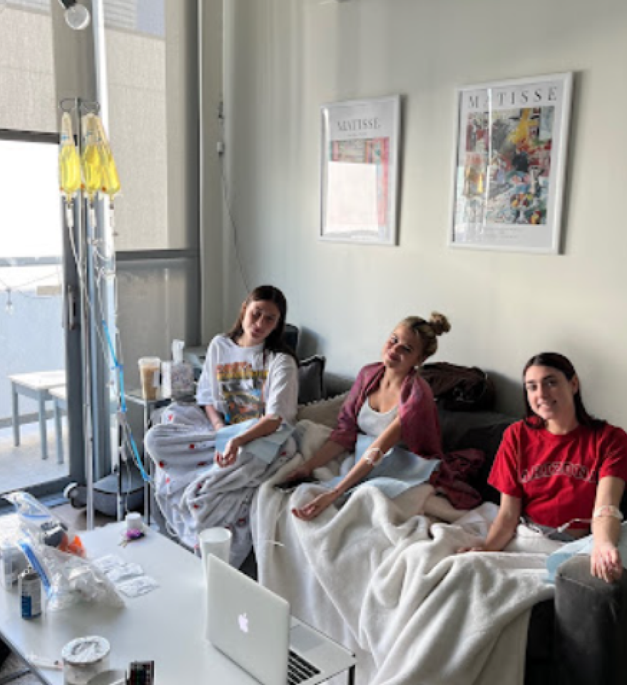 Three women are sitting on a couch in a living room.