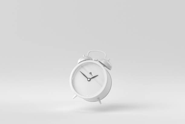 A white alarm clock is floating in the air on a white background.