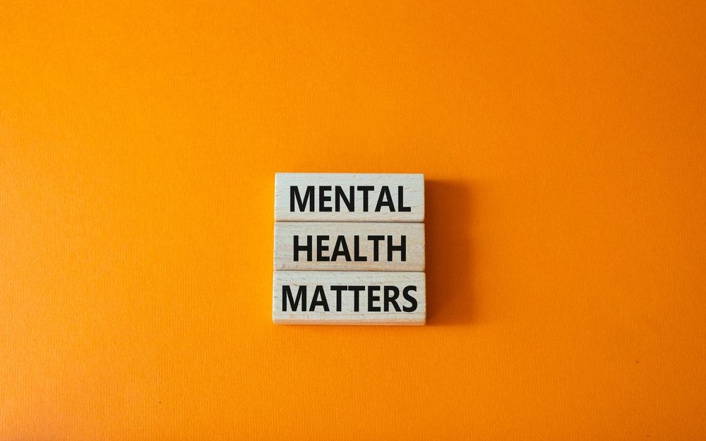 Mental health matters is written on wooden blocks on an orange background.