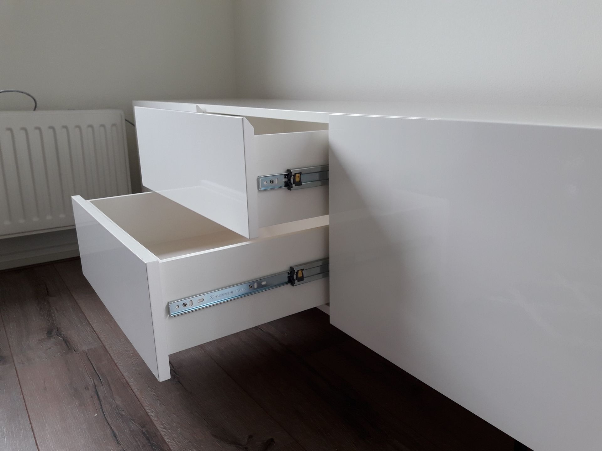 Op maat gemaakt hoogglans wit TV meubel met greeploze en zachtsluitende deuren en lades.