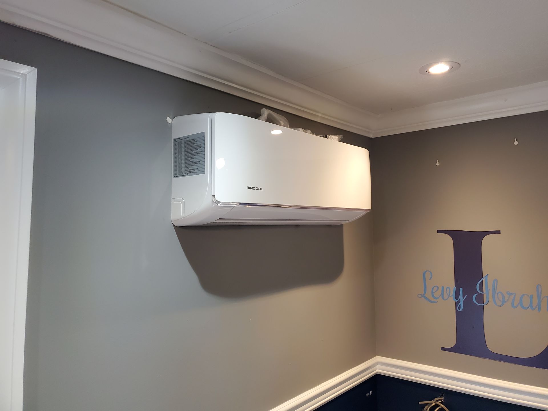A white air conditioner is hanging from the ceiling in a room.