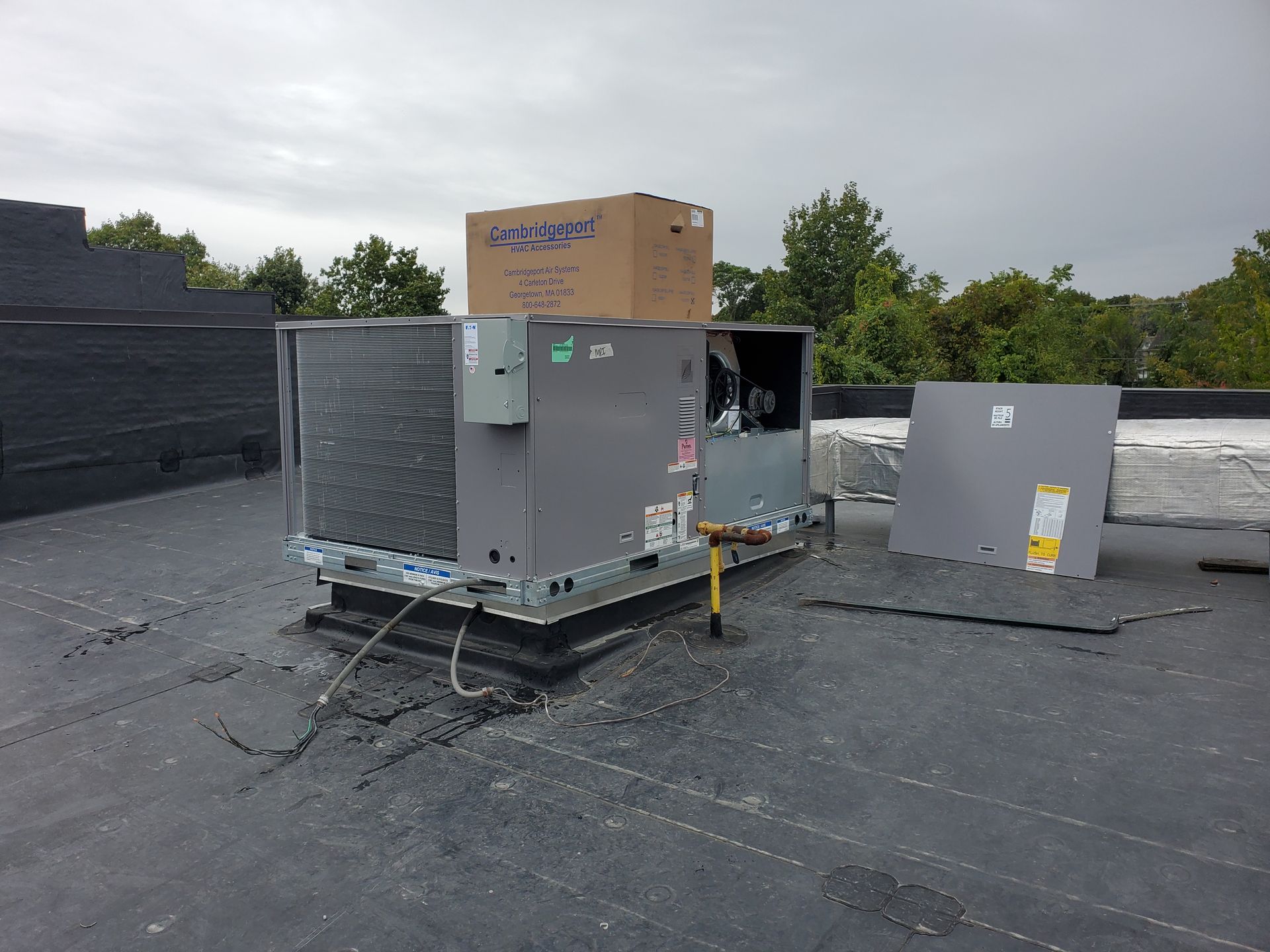 An air conditioner is sitting on top of a roof with a box on top of it.