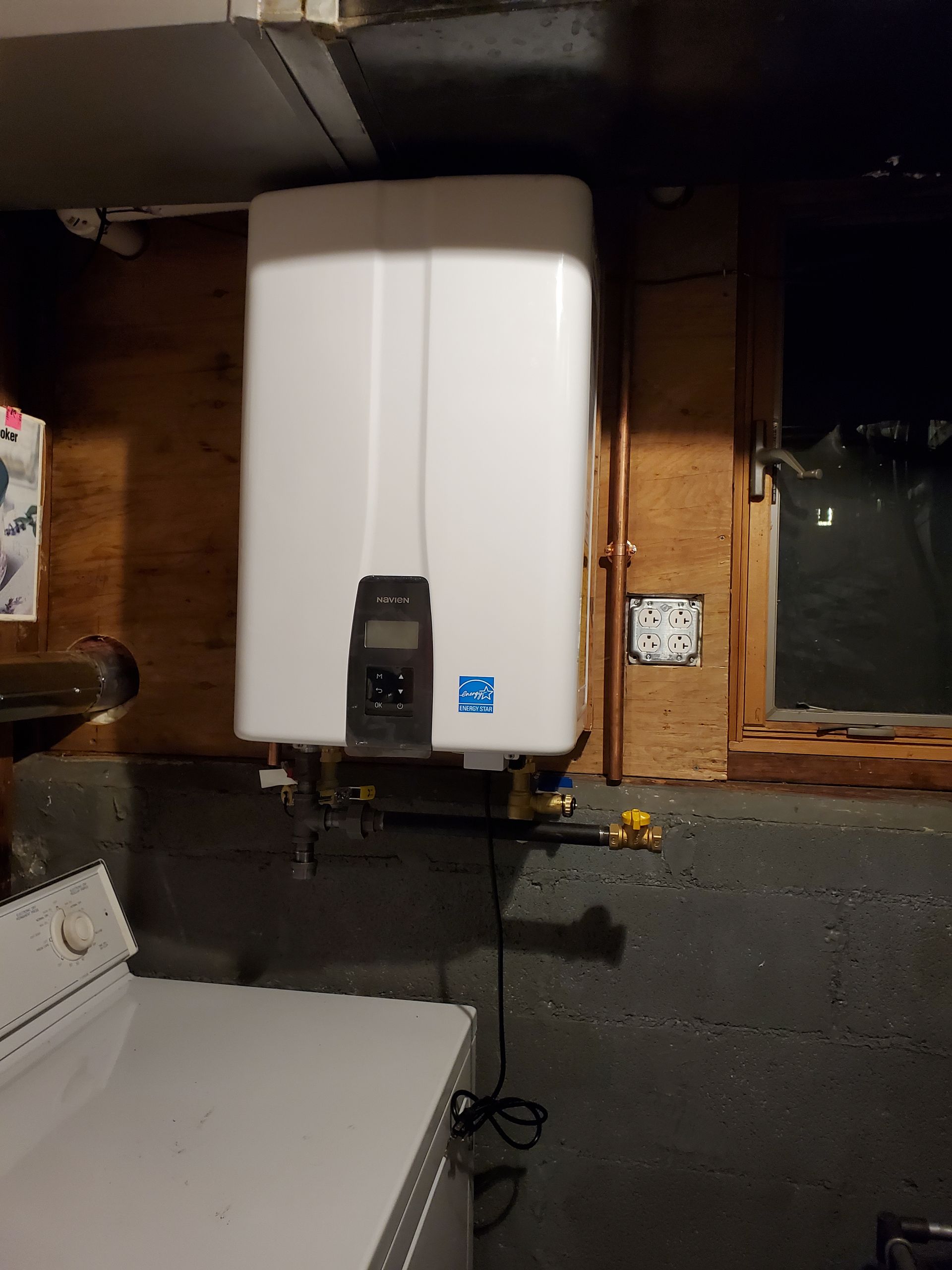 A white water heater is sitting in a laundry room next to a washer and dryer.