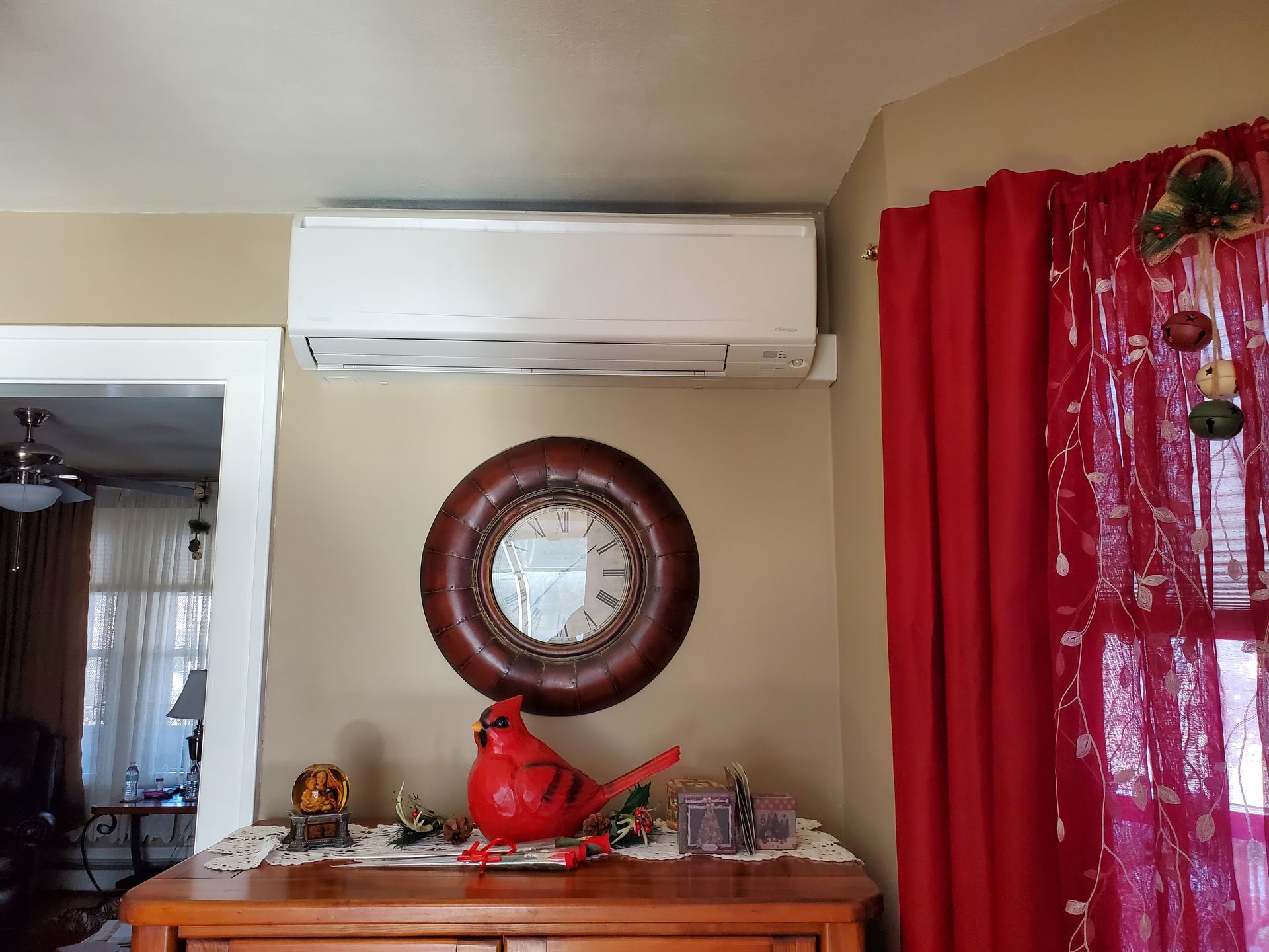 There is a clock on the wall above the dresser in the living room.