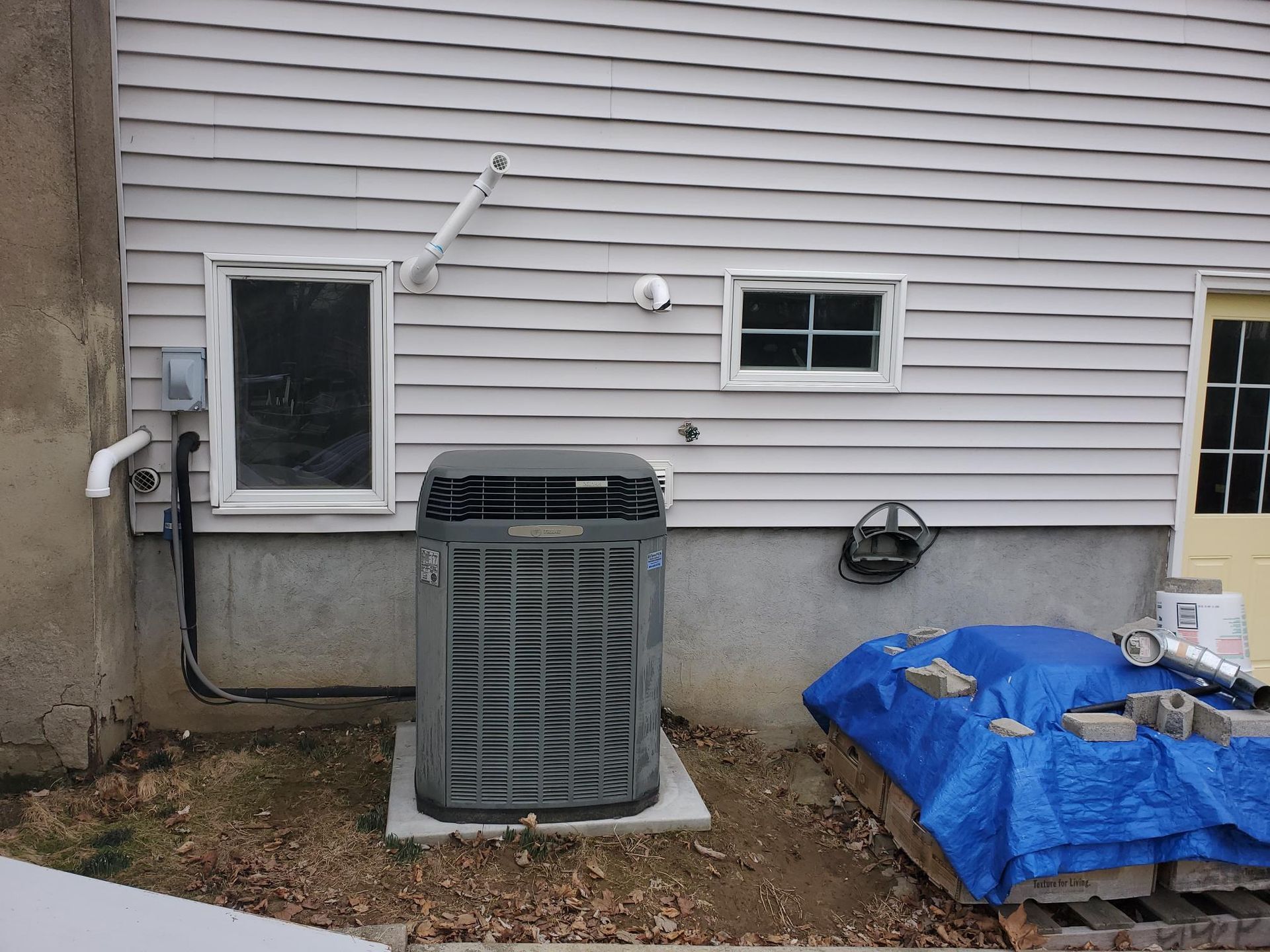 An air conditioner is sitting on the side of a house.