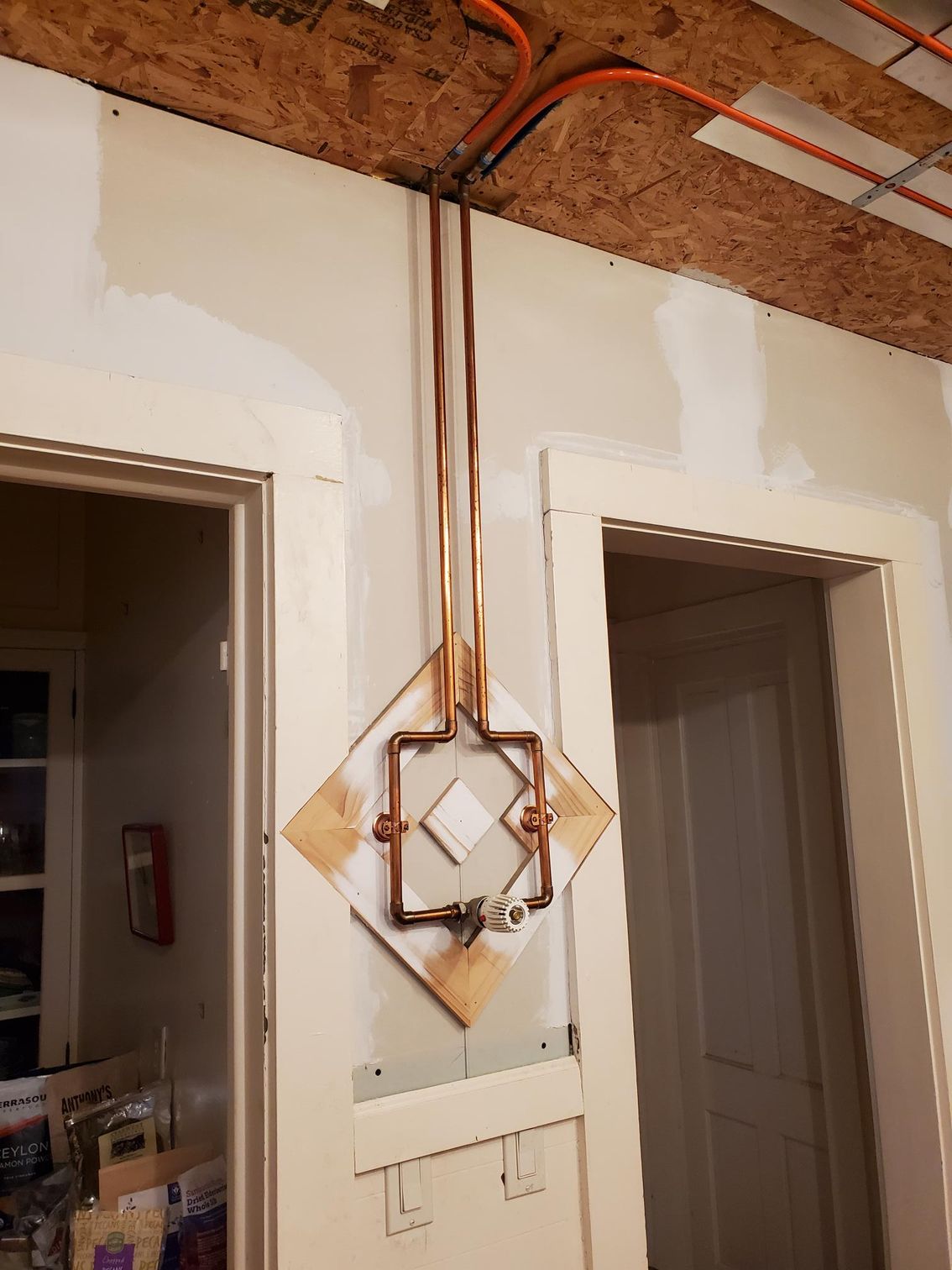 A copper pipe is hanging from the ceiling in a room.