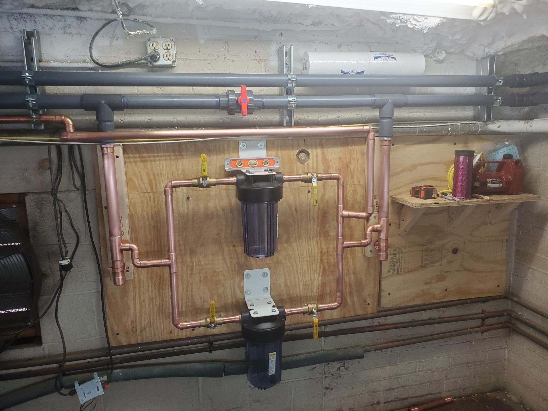 A room with a lot of pipes and a water filter on the wall.