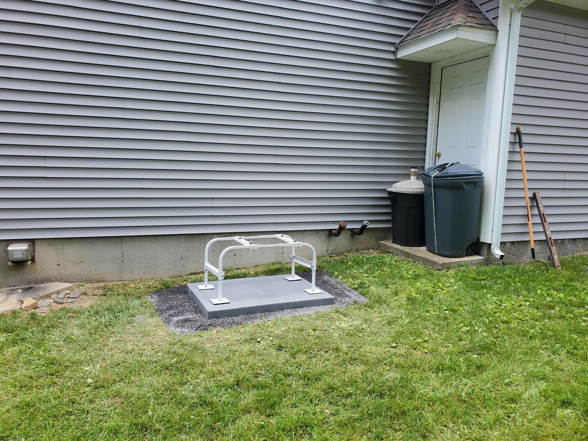 A bicycle rack is sitting in the grass in front of a house.