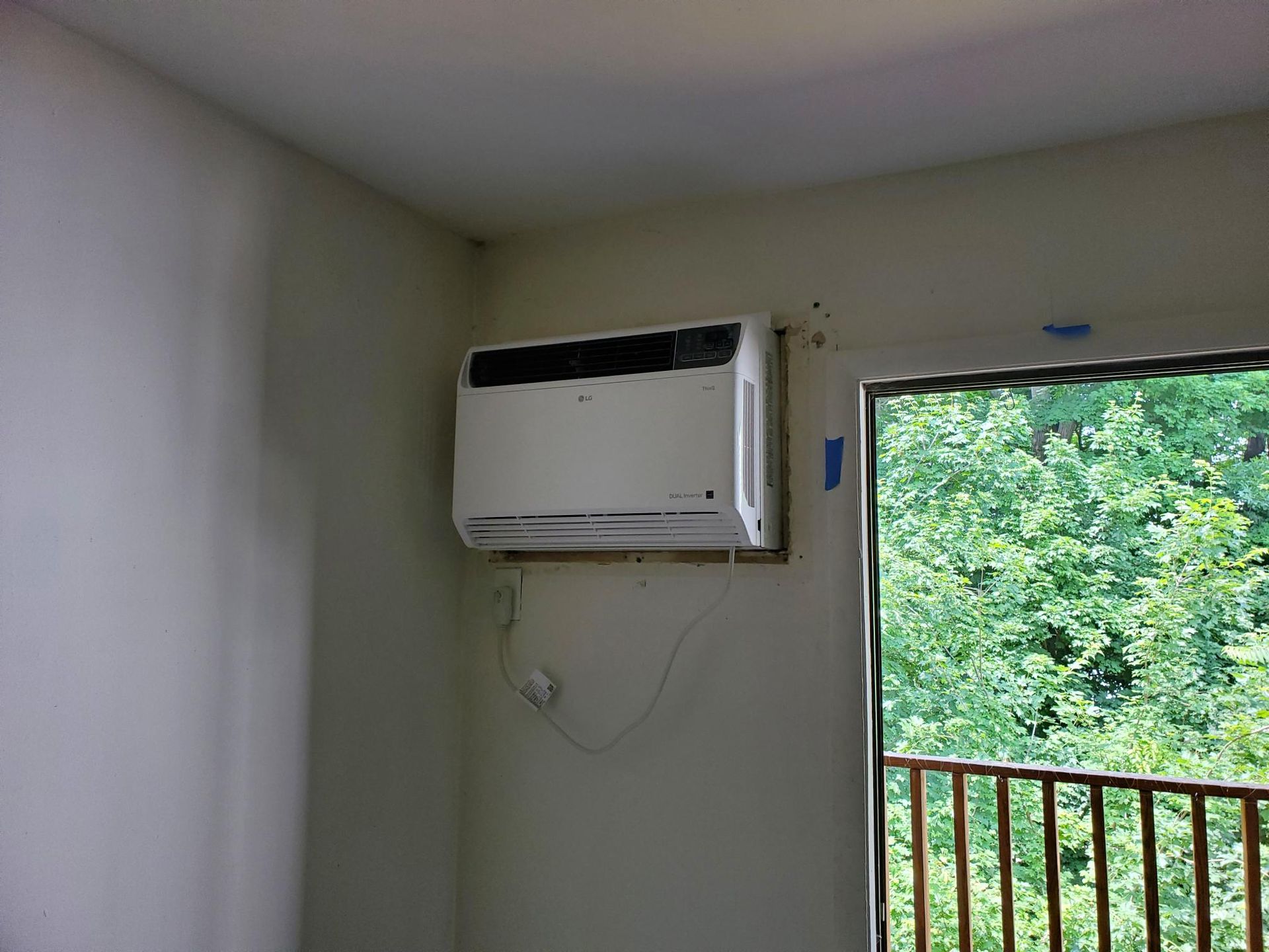 A room with a window and an air conditioner on the wall.
