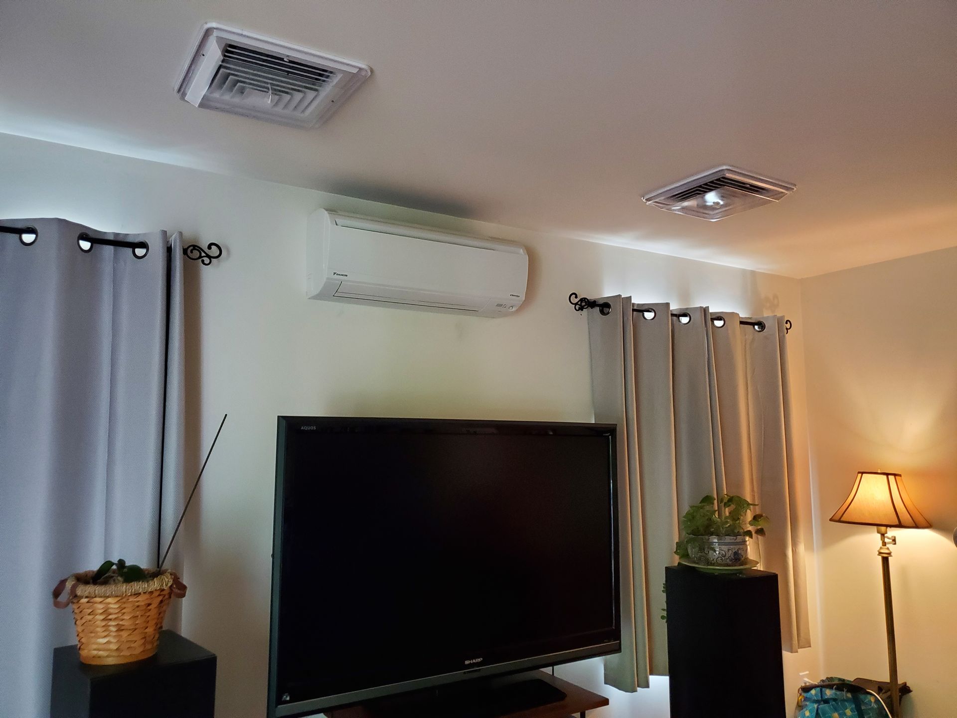 A living room with a flat screen tv and air conditioner.