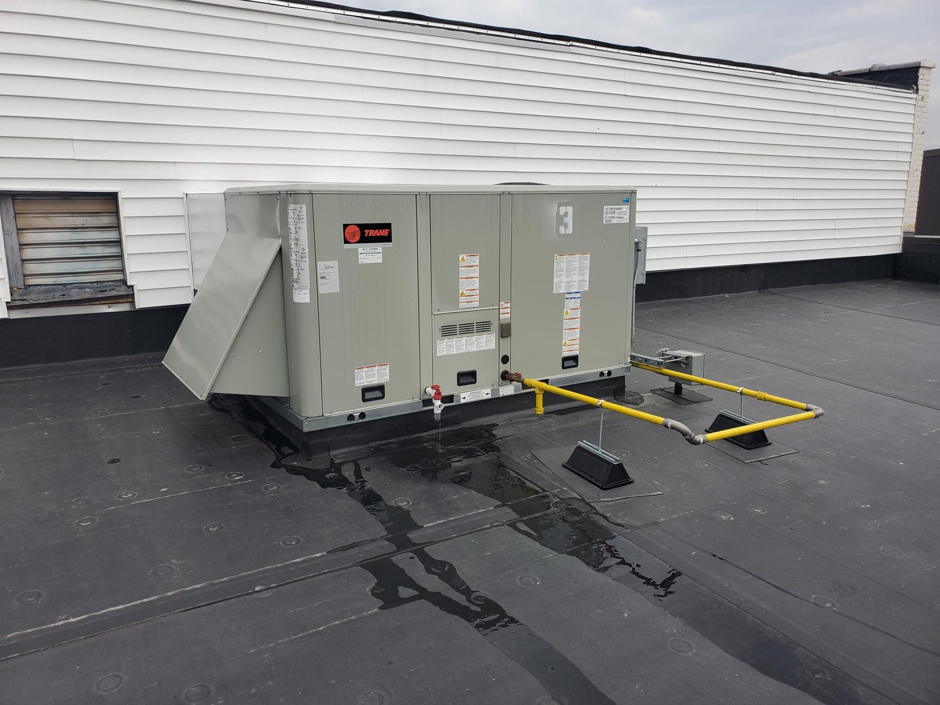 A large air conditioner is sitting on the roof of a building.