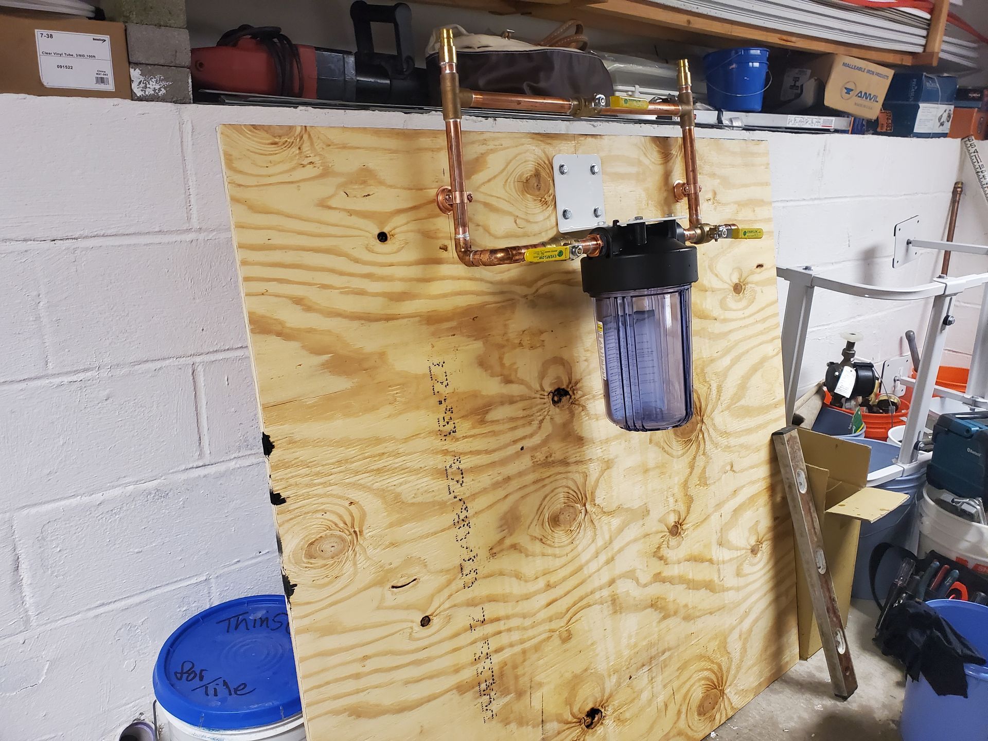 A water filter is hanging on a wooden wall in a garage.
