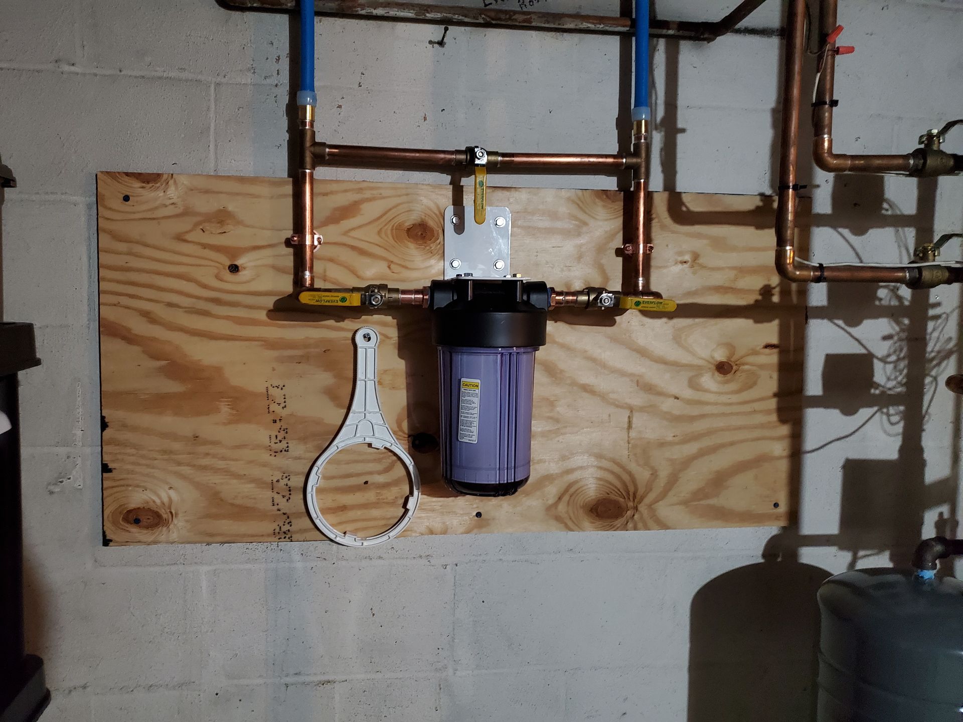 A purple water filter is mounted to a wooden board