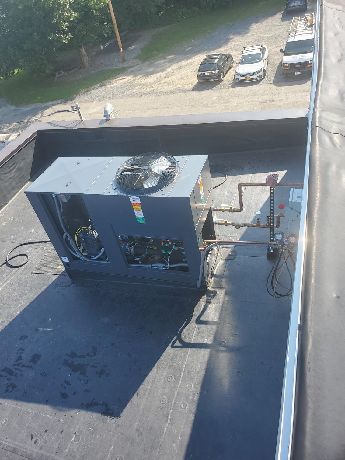 A large box is sitting on top of a roof next to a parking lot.
