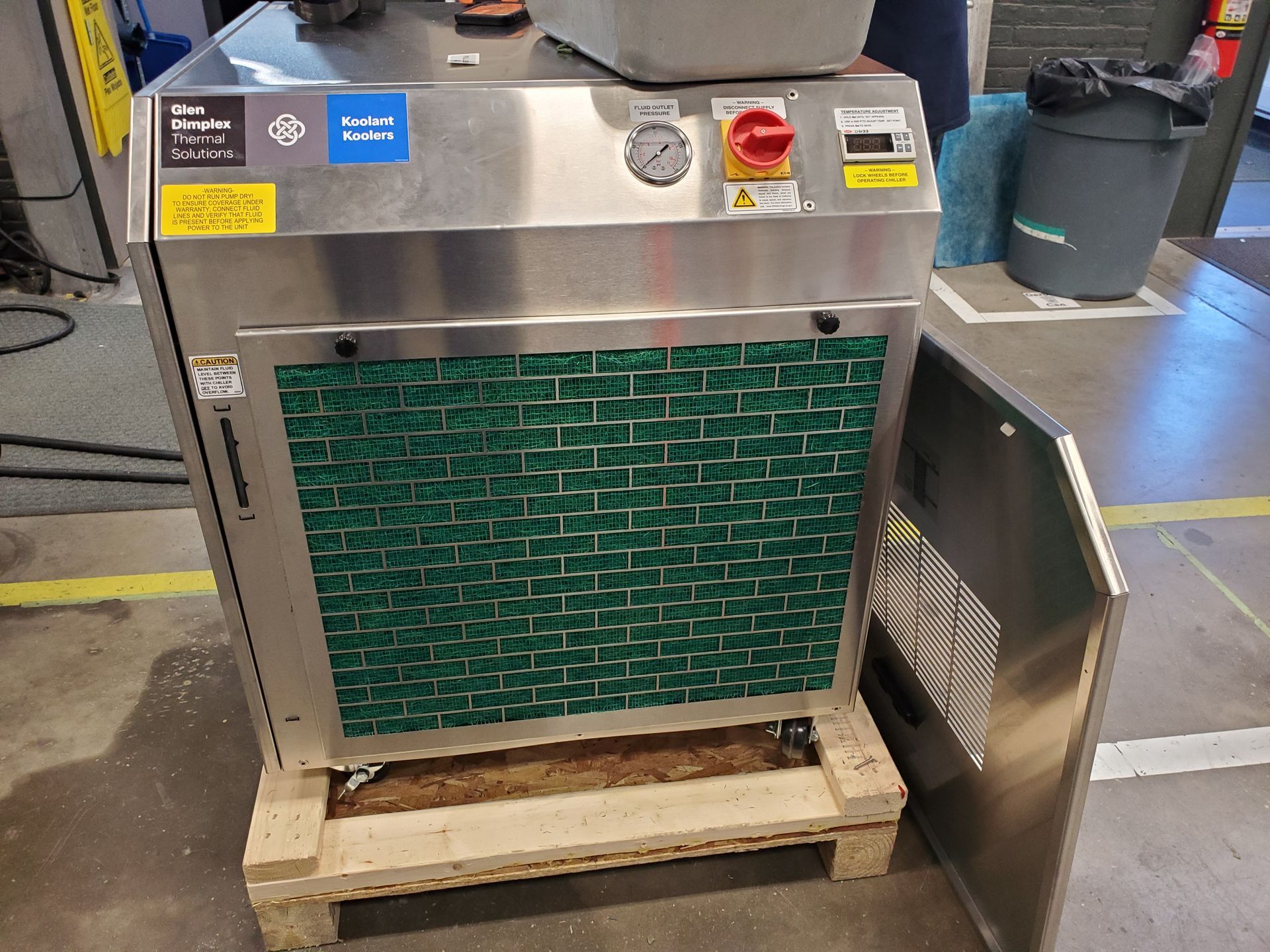 A stainless steel machine is sitting on a wooden pallet.
