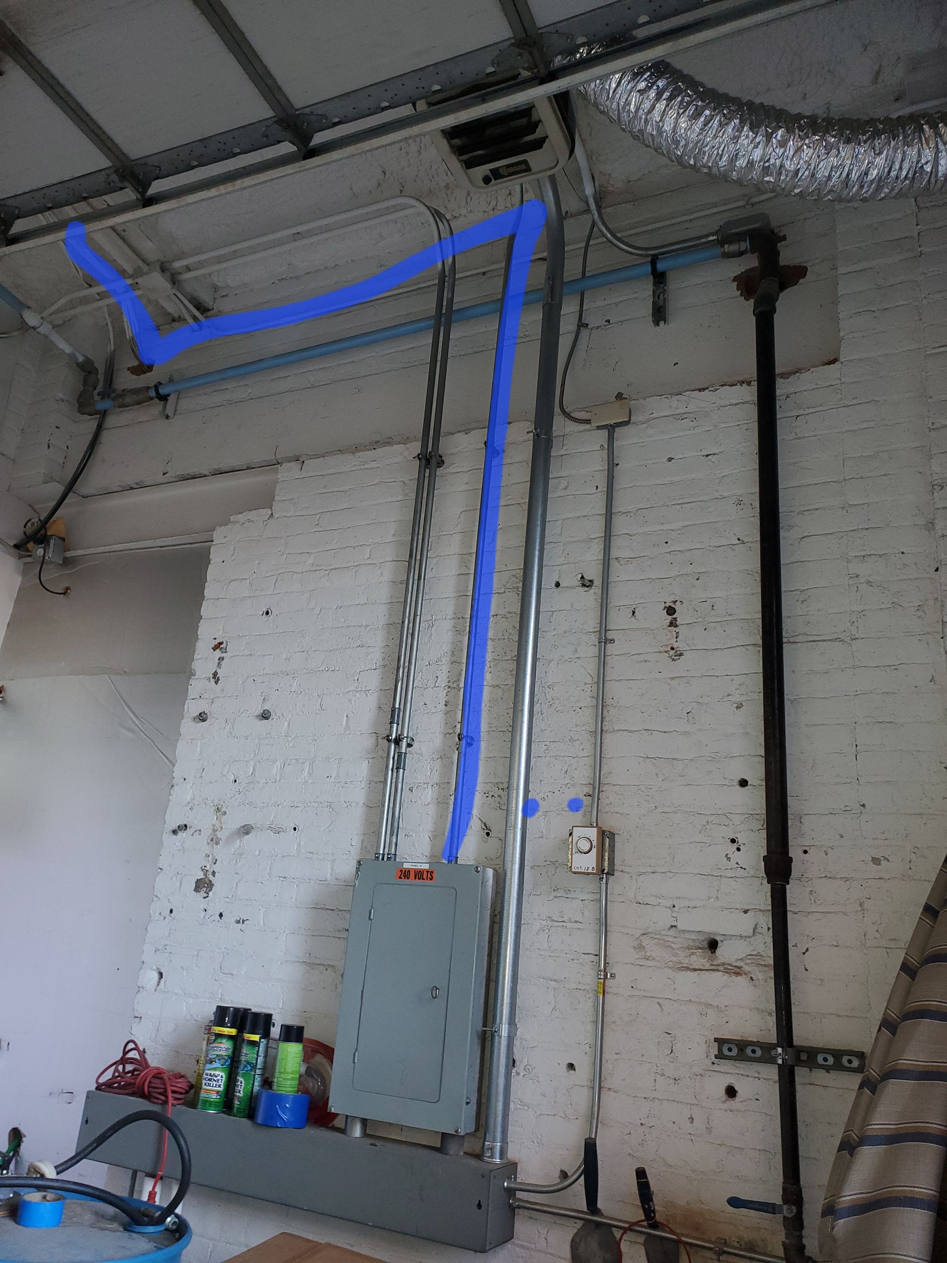 A white brick wall with blue pipes coming out of it