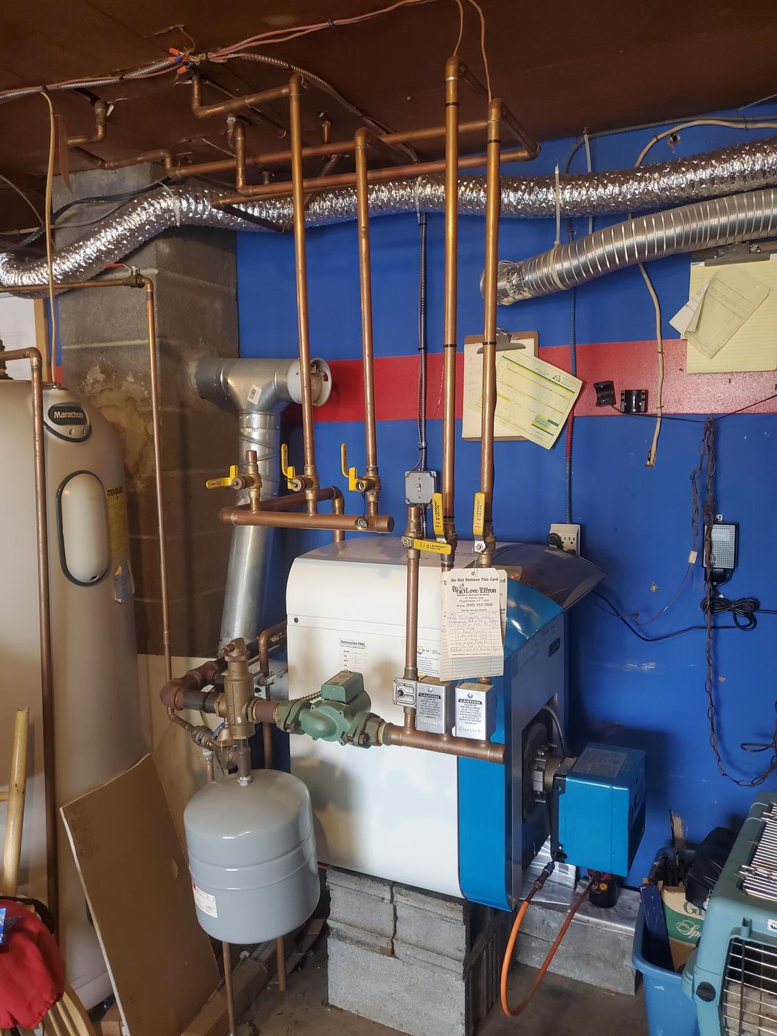 A blue and white boiler is sitting in a room with a blue wall.