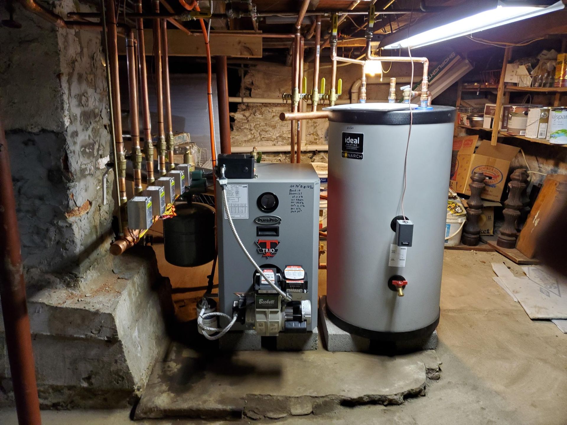 A boiler and a water heater are in a basement.
