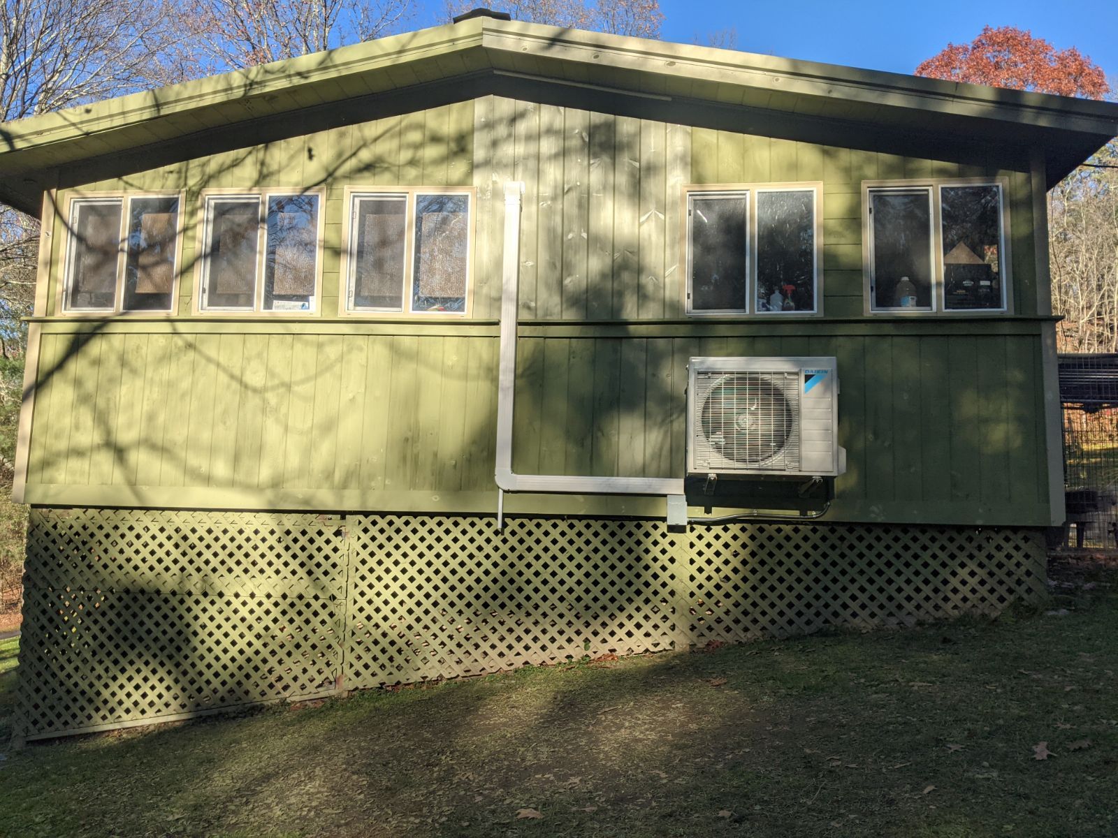 A green house with two air conditioners on the side of it.