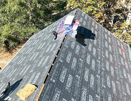 An aerial view of a roof with shingles being installed.