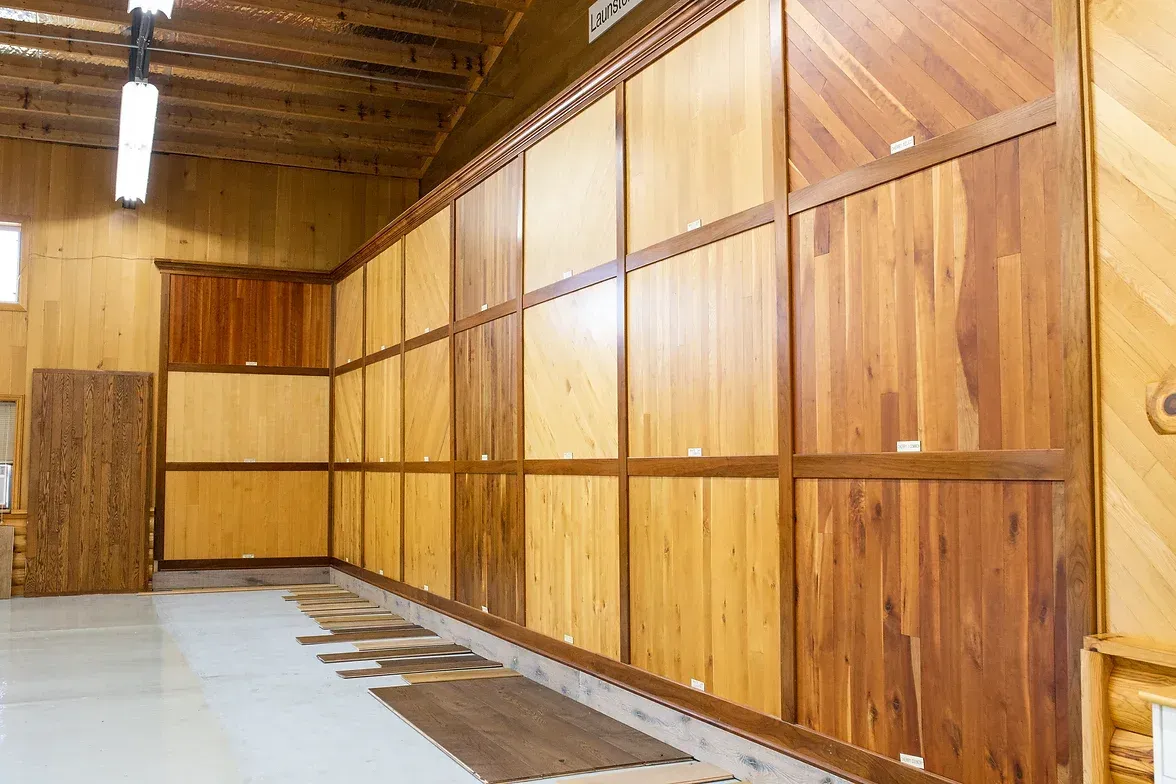A kitchen with stainless steel appliances , black cabinets , wooden floors and a large window.