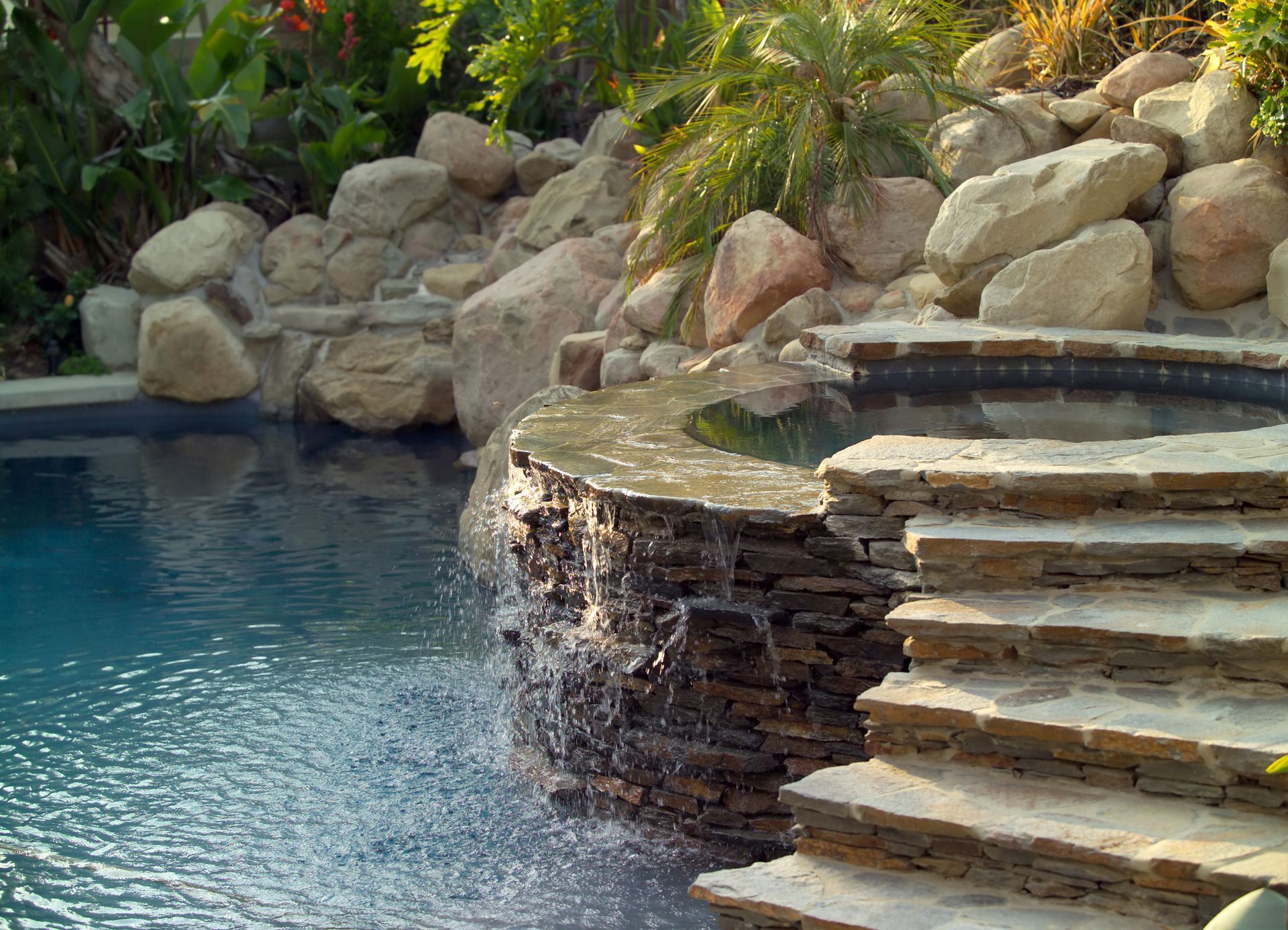 A swimming pool with stairs leading up to it and a waterfall