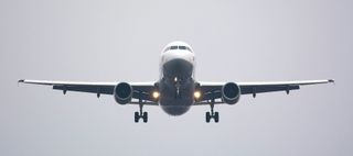 A large passenger jet is flying through a cloudy sky.