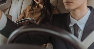 A man and a woman are sitting in the back seat of a car.