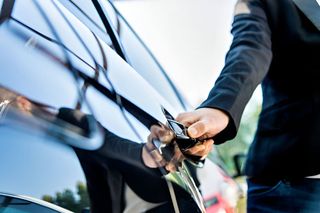 A man is opening the door of a car with a key.